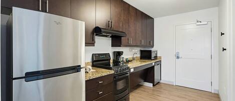 A modern kitchen with dark cabinets, stainless steel appliances, and a granite countertop.