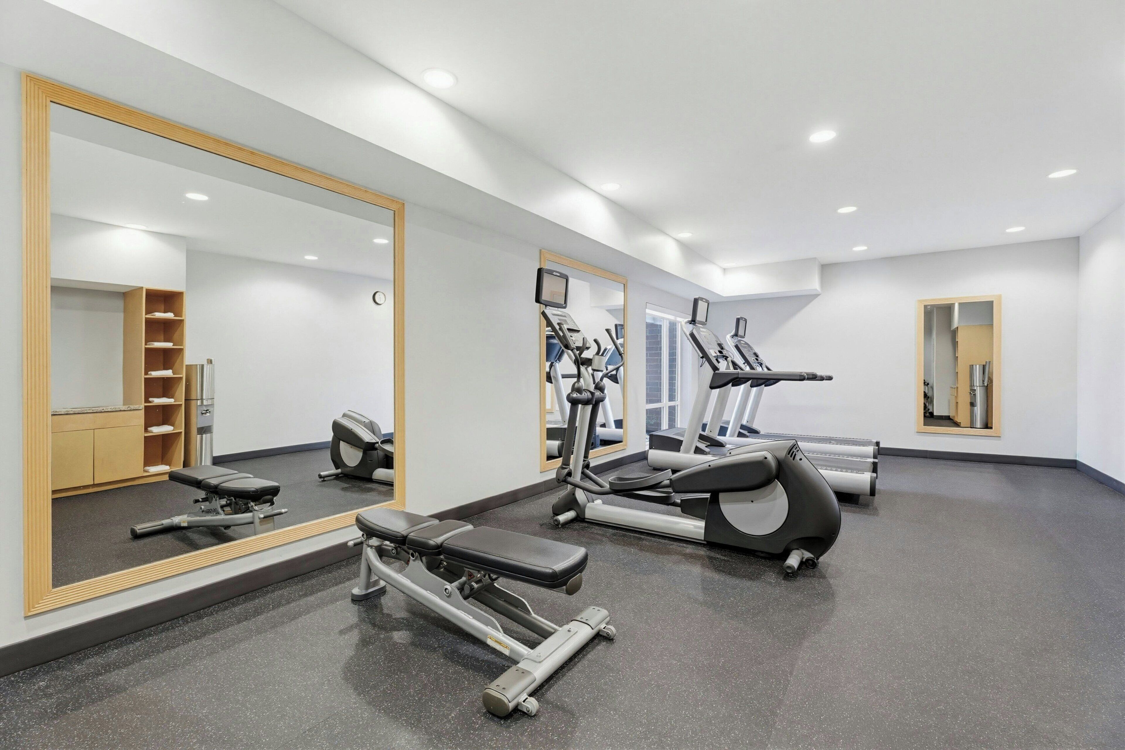A gym with exercise equipment, mirrors, and a clean, modern design.