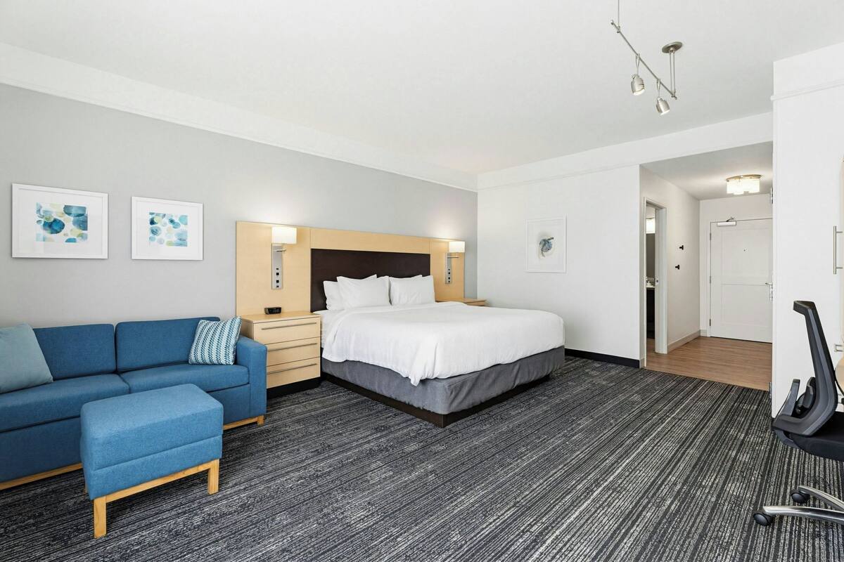 A hotel room with a bed, a sofa, a desk, and a chair.