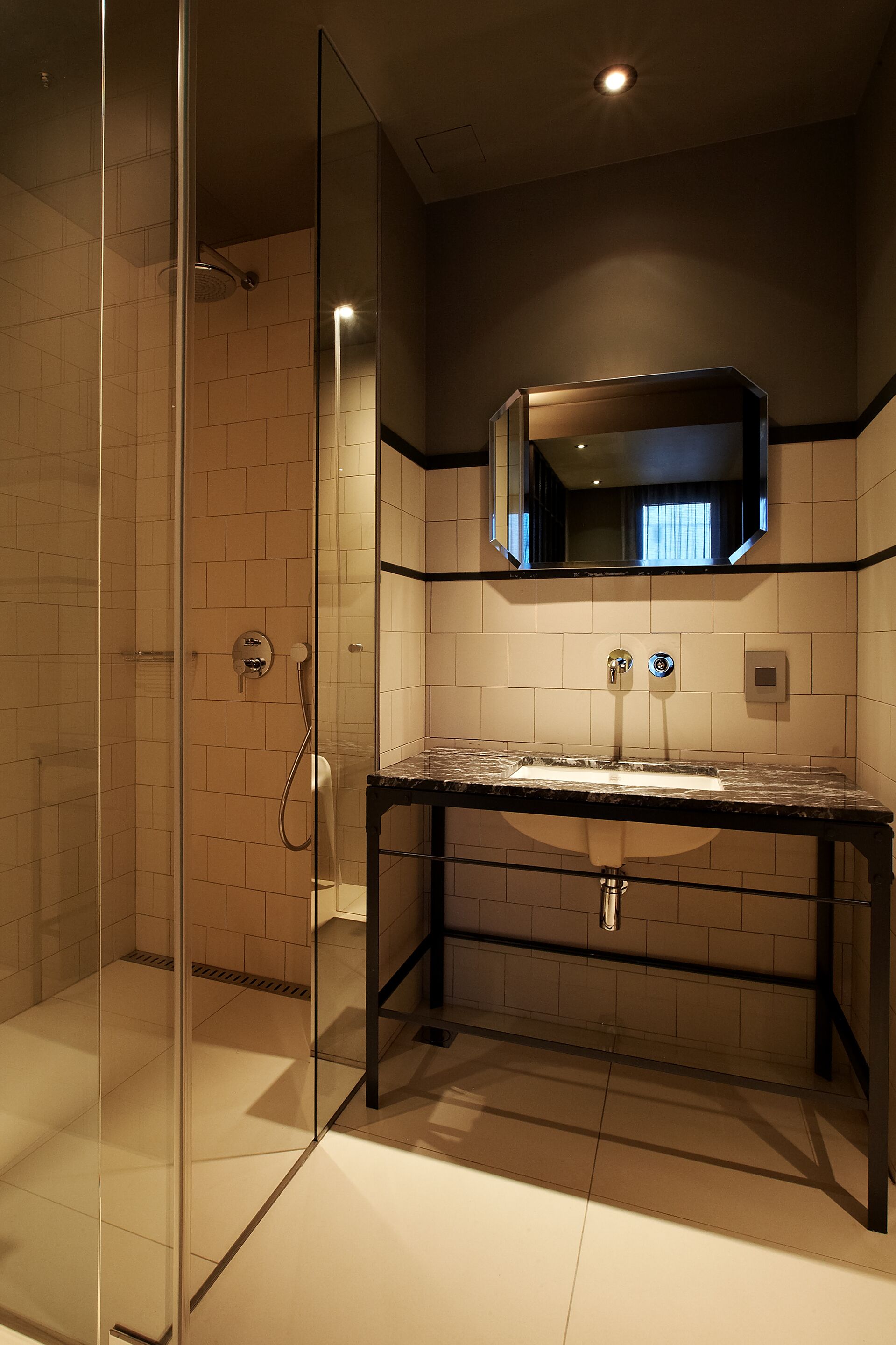 A modern bathroom with a glass shower enclosure, a marble sink, and a mirror above the sink.