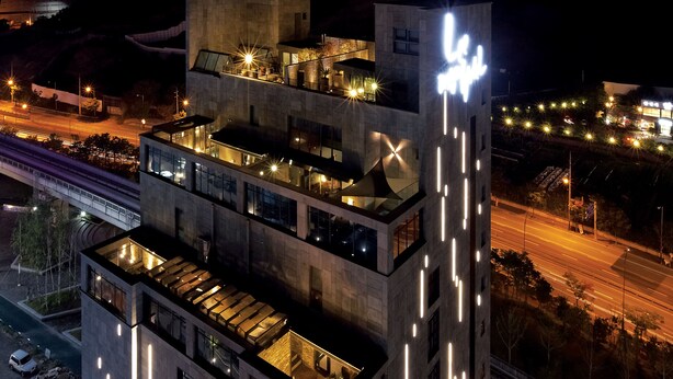 A multi-story building with illuminated balconies and a prominent sign on the top. - Lee Design Hotel (Yongin)