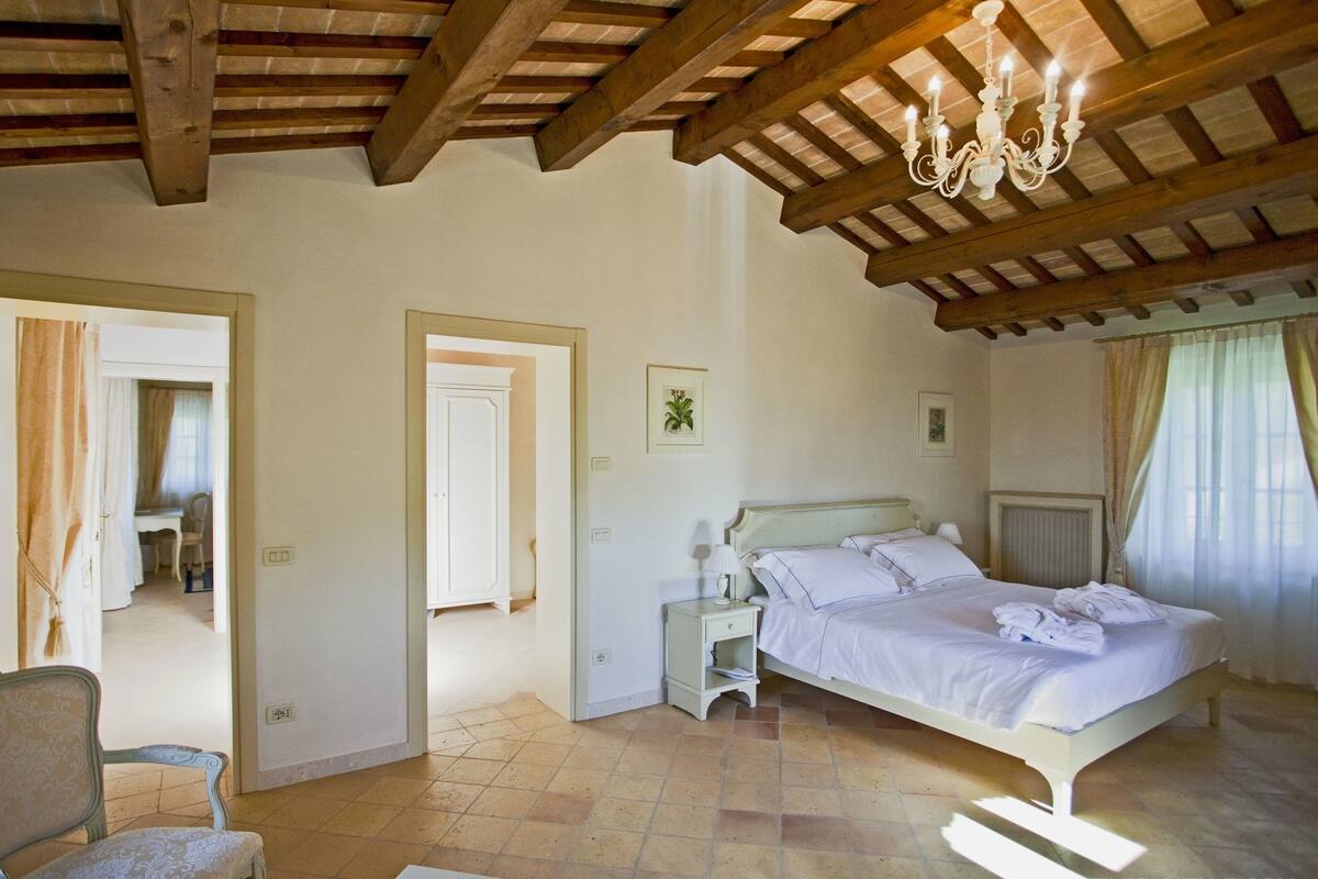 Une chambre à coucher avec un lit, une chaise, un bureau et un lustre.