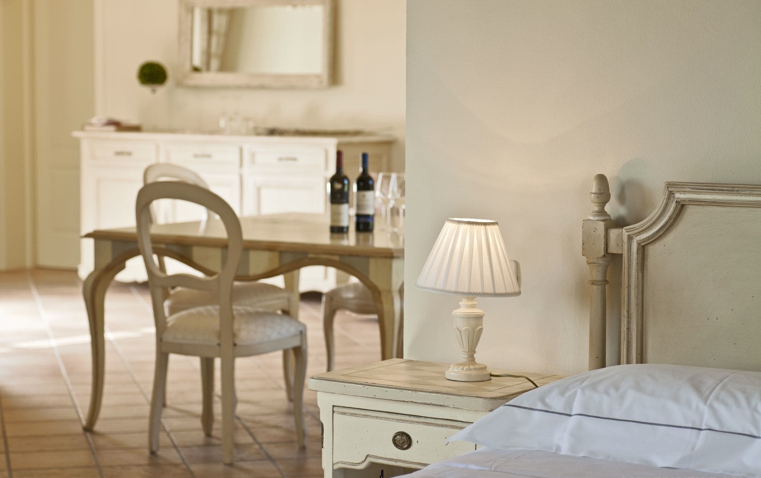 Une chambre à coucher comprenant un lit, une table de chevet avec une lampe, une chaise, une commode et un miroir.