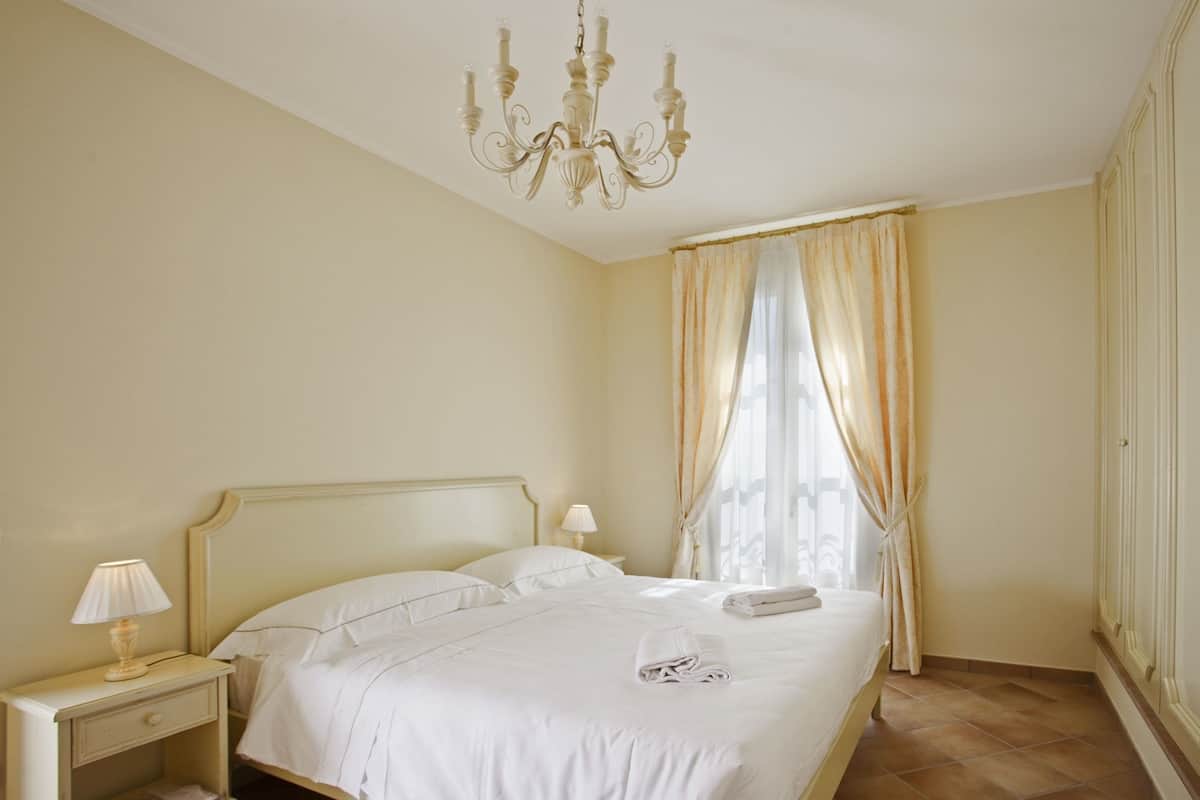 Une chambre d’hôtel avec un lit, une table de chevet, une lampe et un lustre.