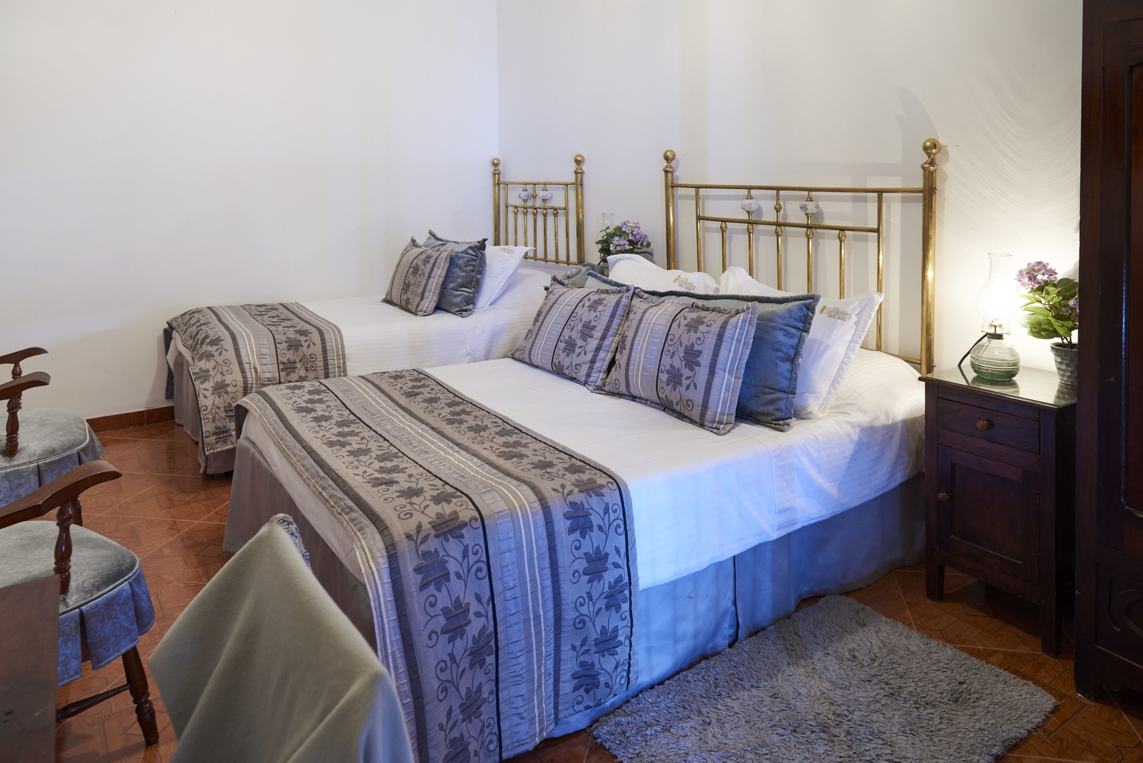 A bedroom with two single beds, a wooden nightstand, a chair, and a small table.