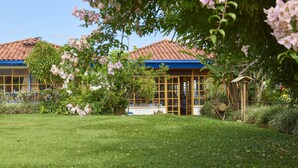 A building with a tiled roof and large windows, surrounded by a well-maintained lawn and flowering plants. - Finca Hotel Los girasoles (Montenegro)