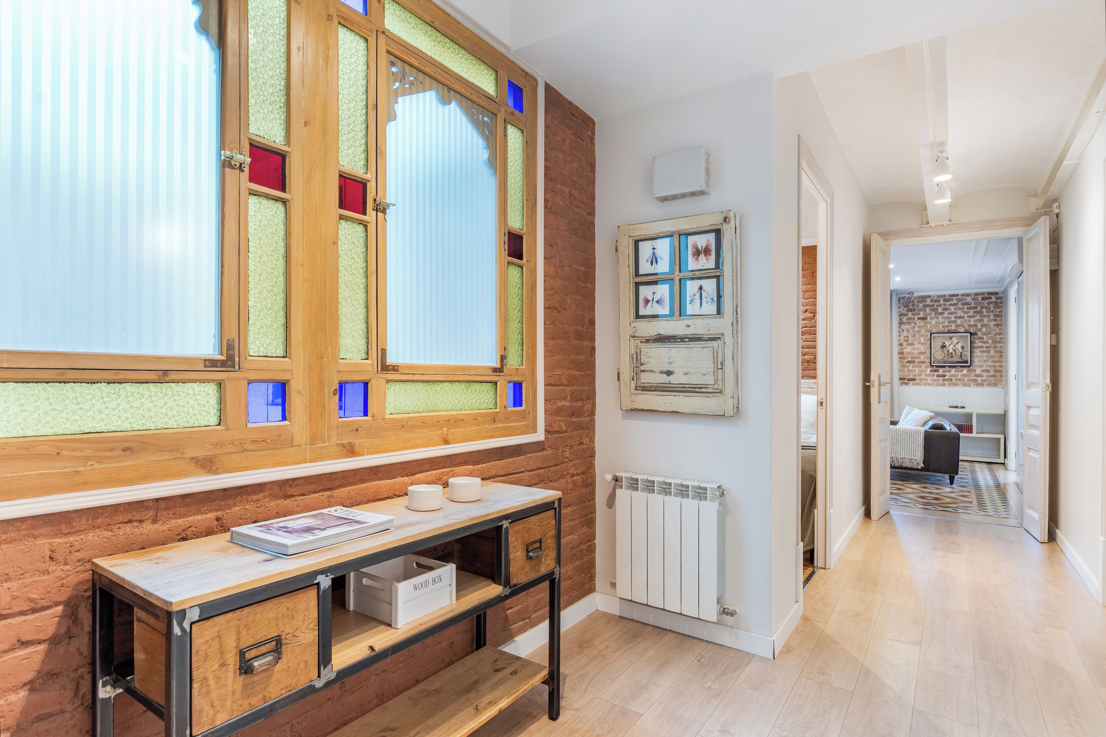 Una habitación con escritorio de madera, radiador y vista a un área de cocina.