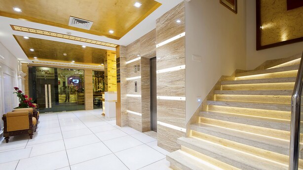 Un hall d’hôtel doté d’un escalier en marbre, d’un comptoir de réception et offrant une vue sur le bar.
