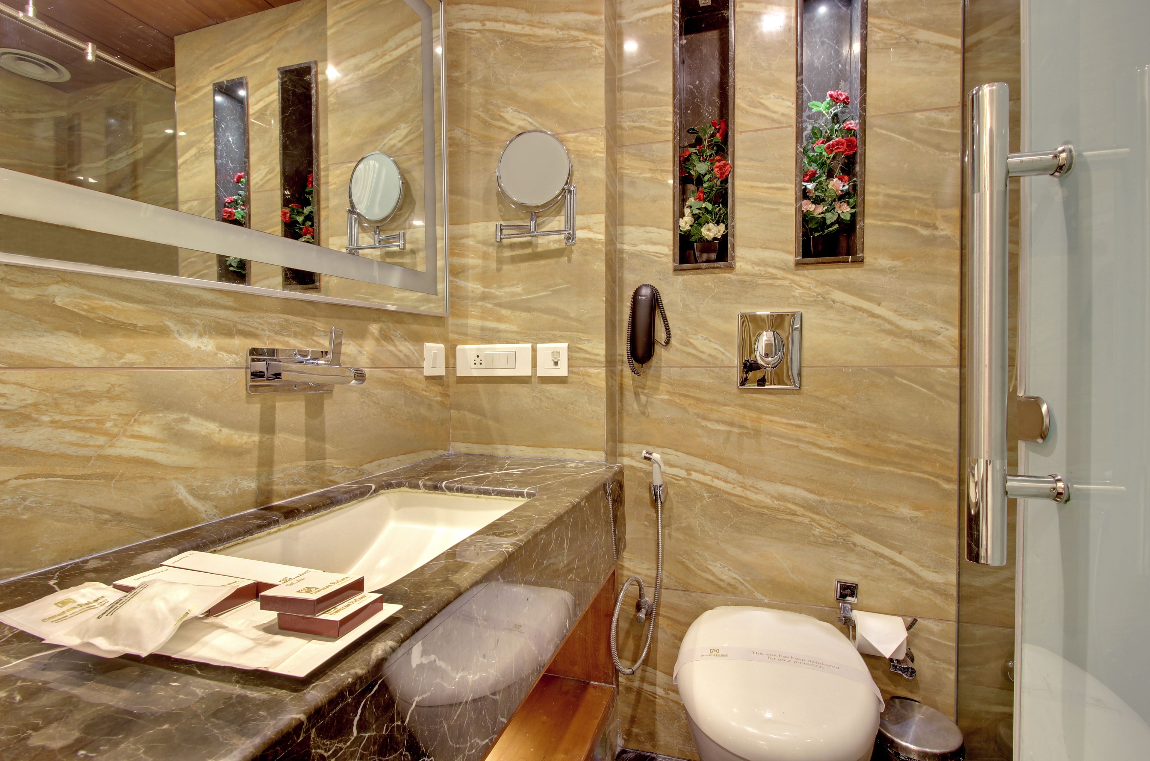 Un baño moderno con un lavamanos de mármol, un espejo grande, un cabezal de ducha manual y un inodoro.