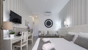 Een moderne hotelkamer met een bed, een bureau, een stoel, een televisie en een grote wandklok.