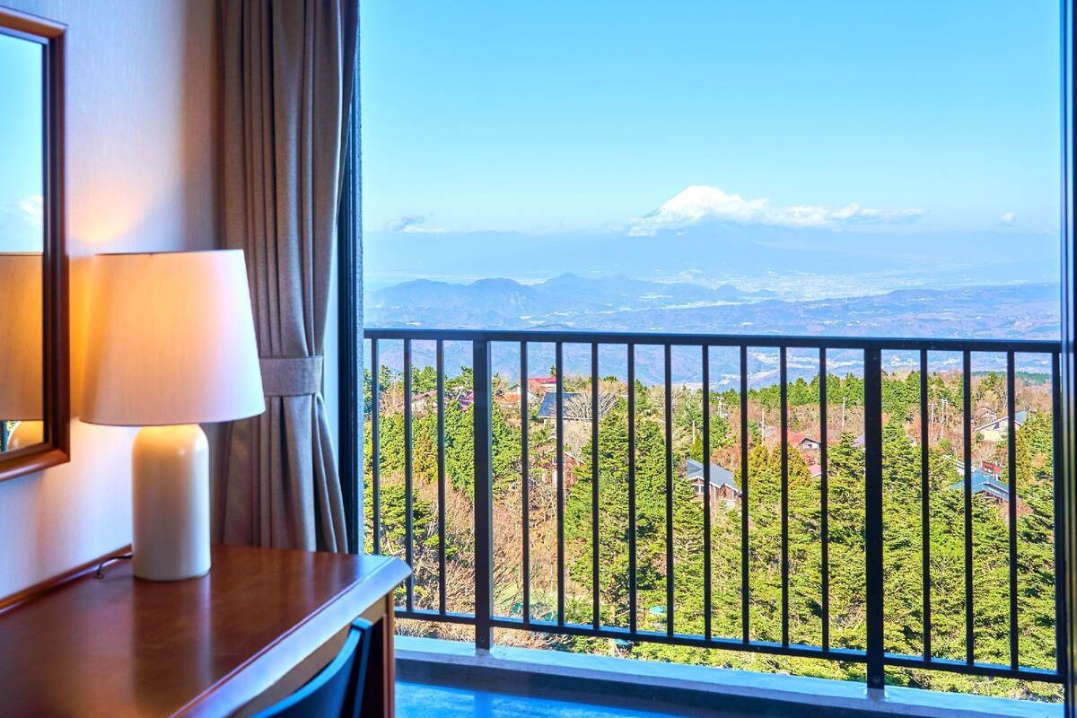 Habitación de hotel con balcón, una lámpara y vistas a un paisaje montañoso.