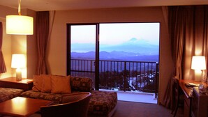 Ein Hotelzimmer mit Balkon, einer Couch, einem Sessel, einem Tisch und zwei Lampen.