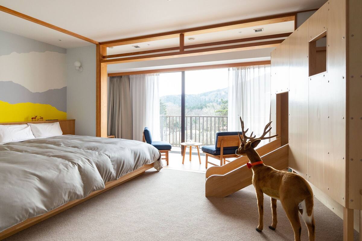 Una habitación de hotel con una cama grande, un balcón con una silla y una estatua de ciervo.