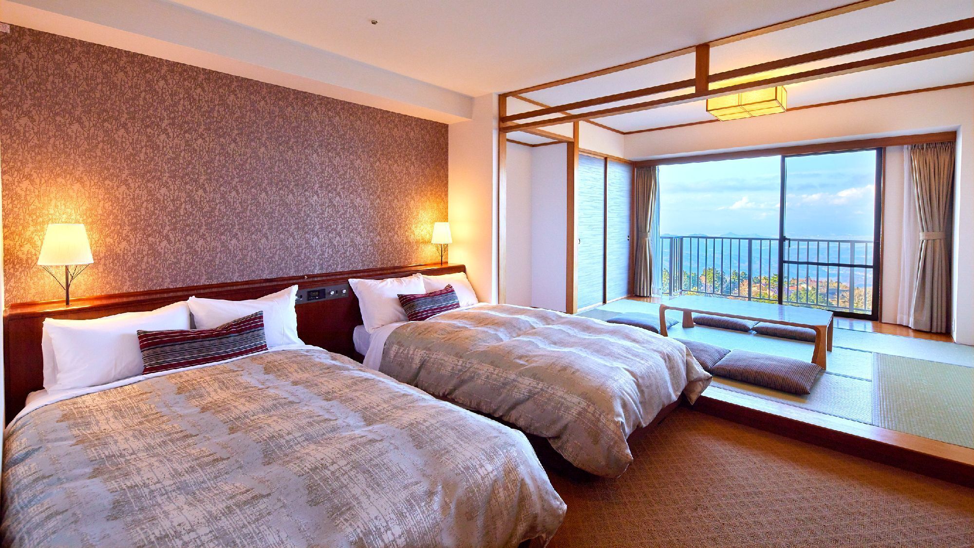 A hotel room with two beds, a balcony with a view, and a patterned wall.