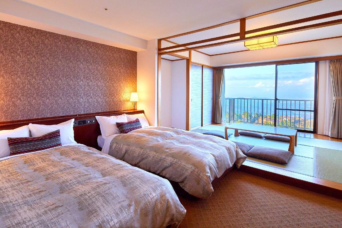 Habitación de hotel con dos camas, un balcón con vistas y una pared con diseño.
