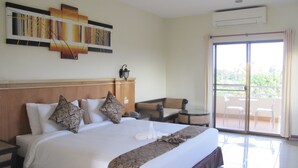 Quarto de hotel com cama grande, mesa pequena, cadeira e varanda com vista.