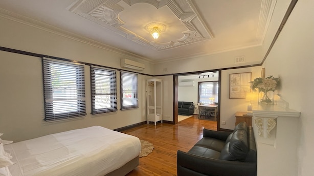 Une chambre à coucher comprenant un lit, un canapé en cuir noir et un coin repas avec une table et des chaises.