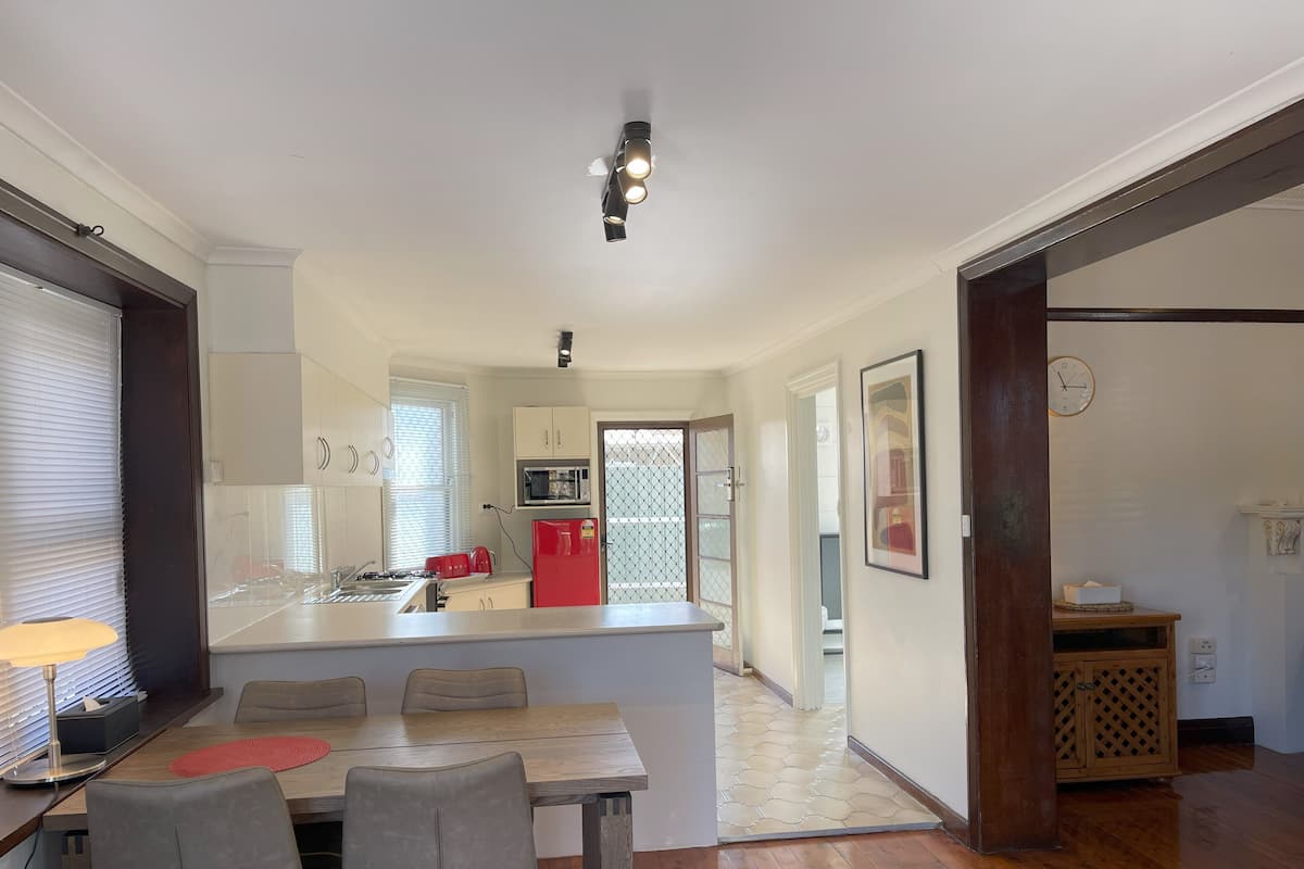 A modern kitchen with a central island, a dining area with two chairs, and a wooden floor.