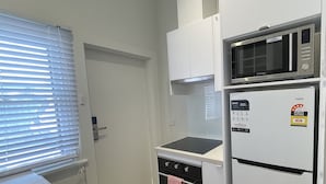 Une cuisine compacte équipée d’un four à micro-ondes encastré, d’un réfrigérateur et d’une cuisinière.