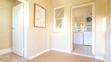 A hallway with a door, a framed map, and a kitchen area with appliances.