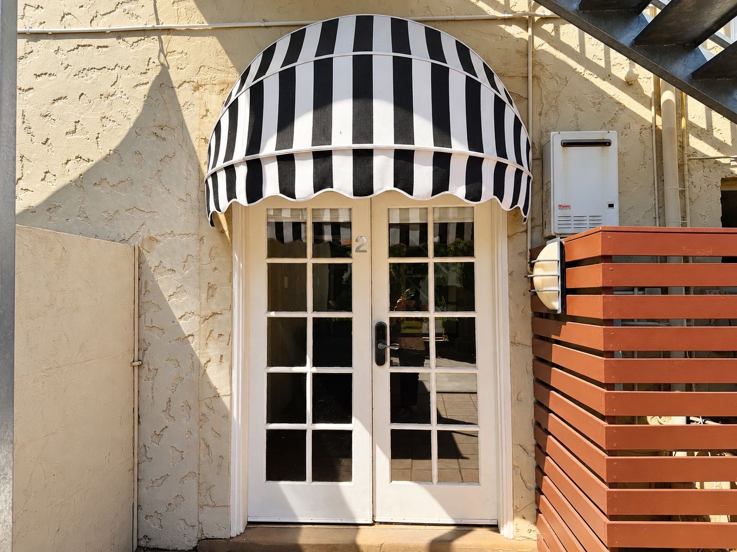 A building with a white door and a black and white striped awning.