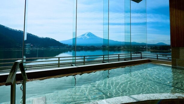 A clear view of Mount Fuji through large windows, a swimming pool, and a wooden deck. - Ubuya (Fujikawaguchiko)