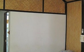 A room with a large white door, wooden paneling on the walls, and a visible electrical outlet on the right side.