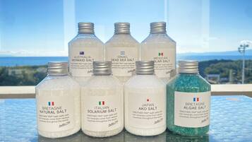 A collection of bath salts on a glass table with a scenic view in the background.