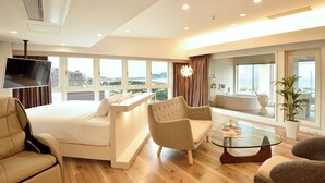 A modern hotel room with a bed, seating area, TV, and large windows. - Breath Hotel (Fujisawa)