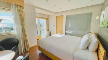 A hotel room with a bed, a desk, a chair, a window with curtains, and a view of the outdoors.