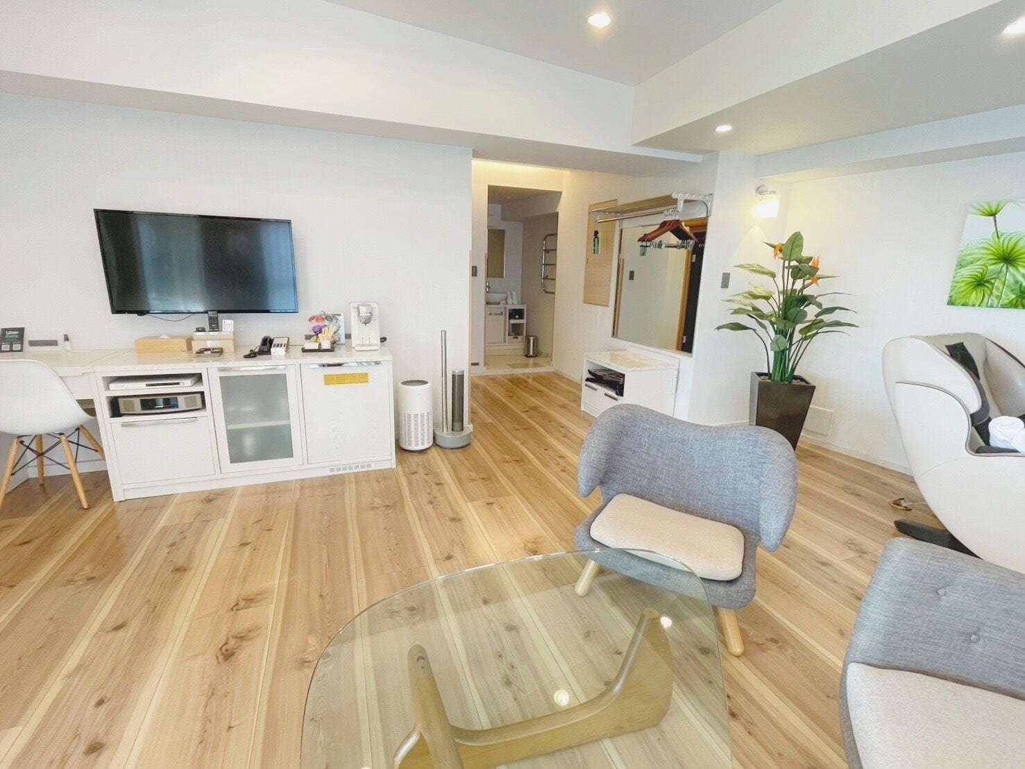 A modern living room with a flat-screen TV, a glass coffee table, and a seating area with two sofas.