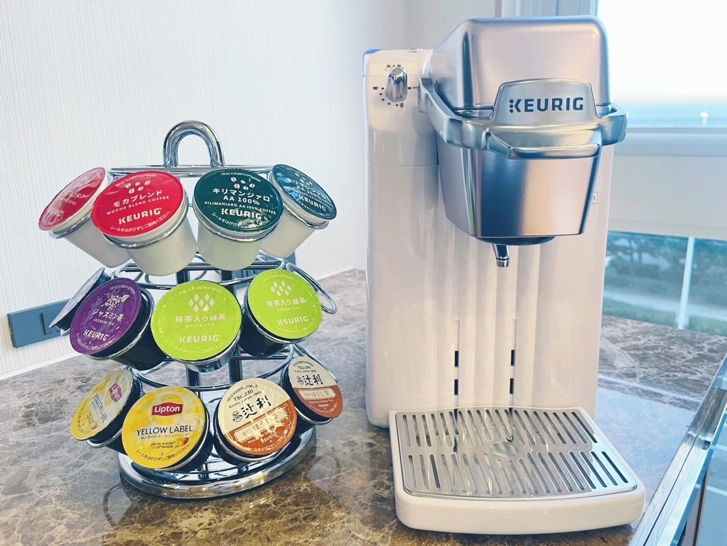 Keurig-kahvinkeitin, jossa on kahvikapseliteline, keittiön työtasolla.