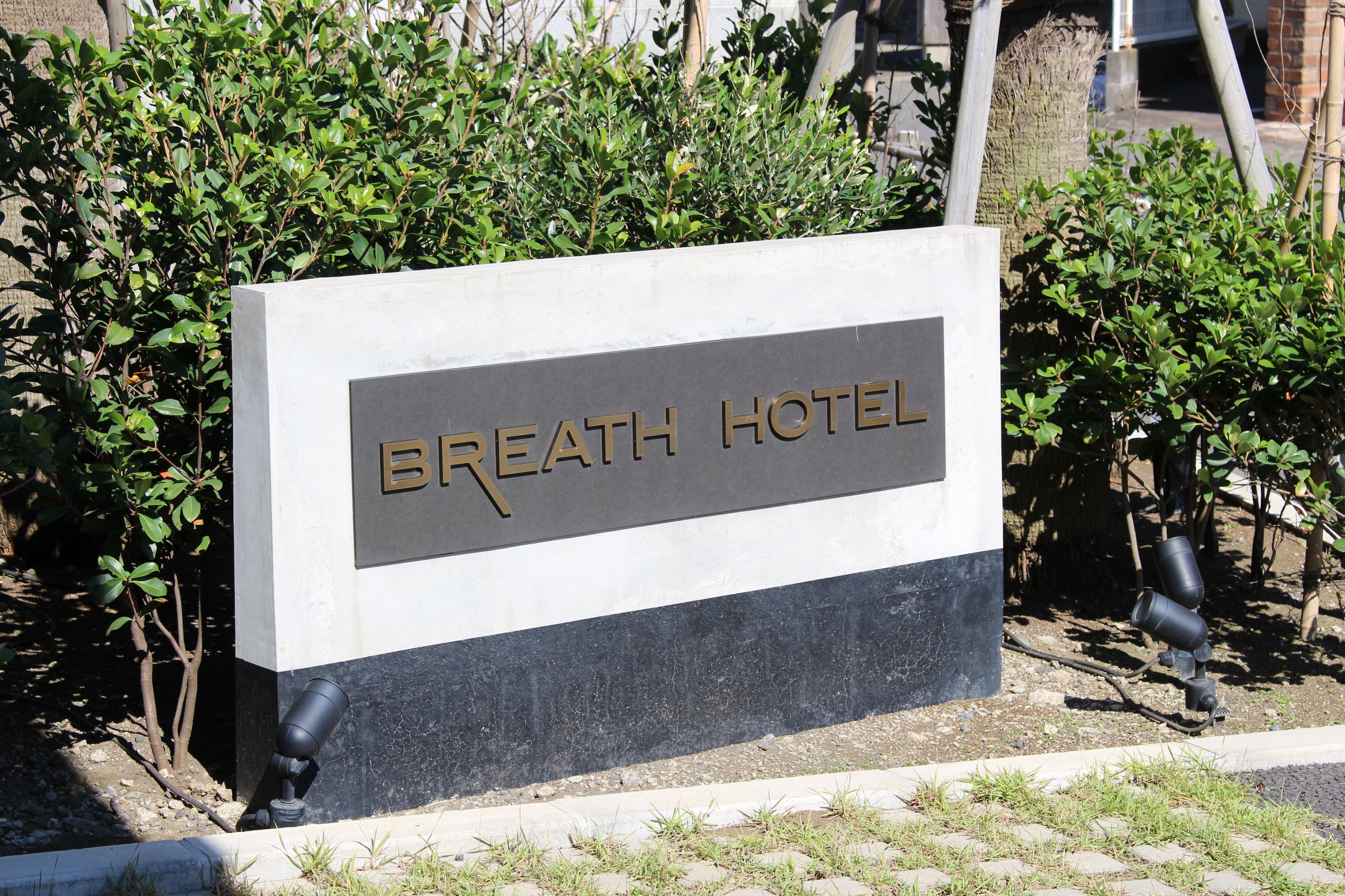 Señal del Hotel Breath con un diseño moderno, rodeado de vegetación.