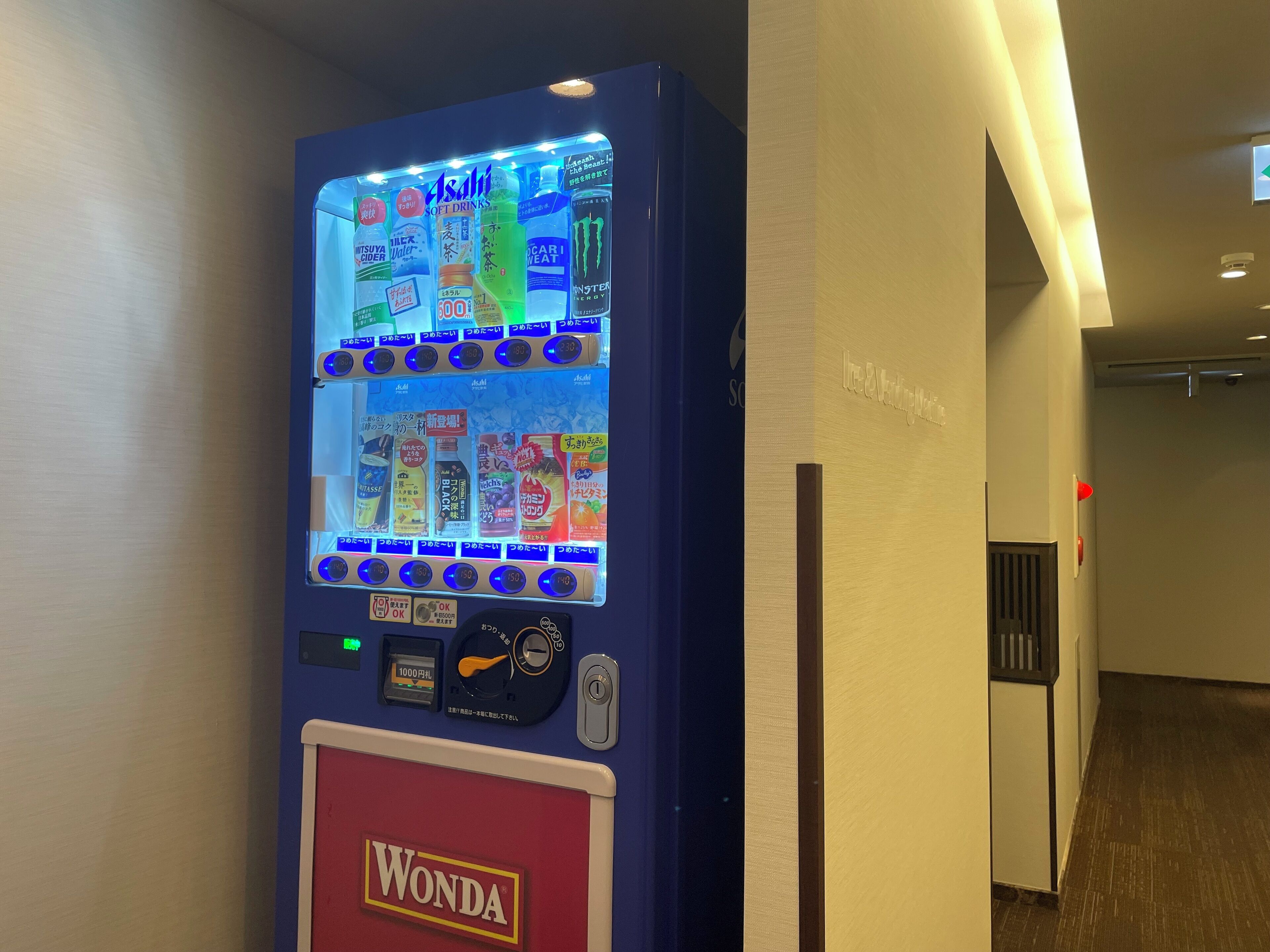 En automattank med olika drycker och snacks, en myntinkast och en Wonda-logotyp.