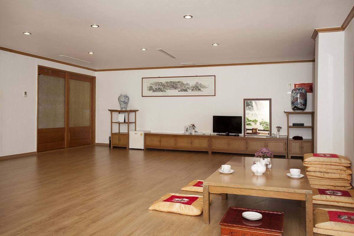 A spacious room with a wooden dining table, chairs, and a television.