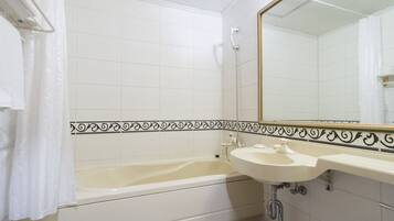 A bathroom with a bathtub, a sink, and a mirror.