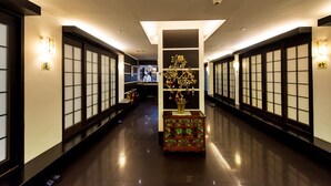 A hallway with traditional Japanese-style sliding doors, a central decorative tree, and a reception desk. - Prado Hotel (Gwangju)