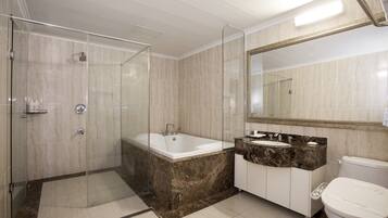 A modern bathroom with a glass-enclosed shower, a freestanding bathtub, a vanity with a marble countertop, and a large mirror.