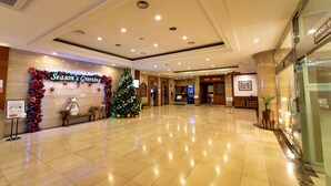 A spacious lobby with a Christmas tree, a 'Season's Greeting' sign, and a reception desk. - Prado Hotel (Gwangju)