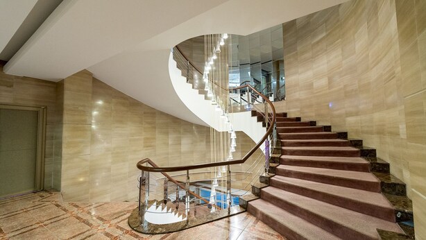 A modern spiral staircase with a glass railing and a polished stone floor. - Prado Hotel (Gwangju)