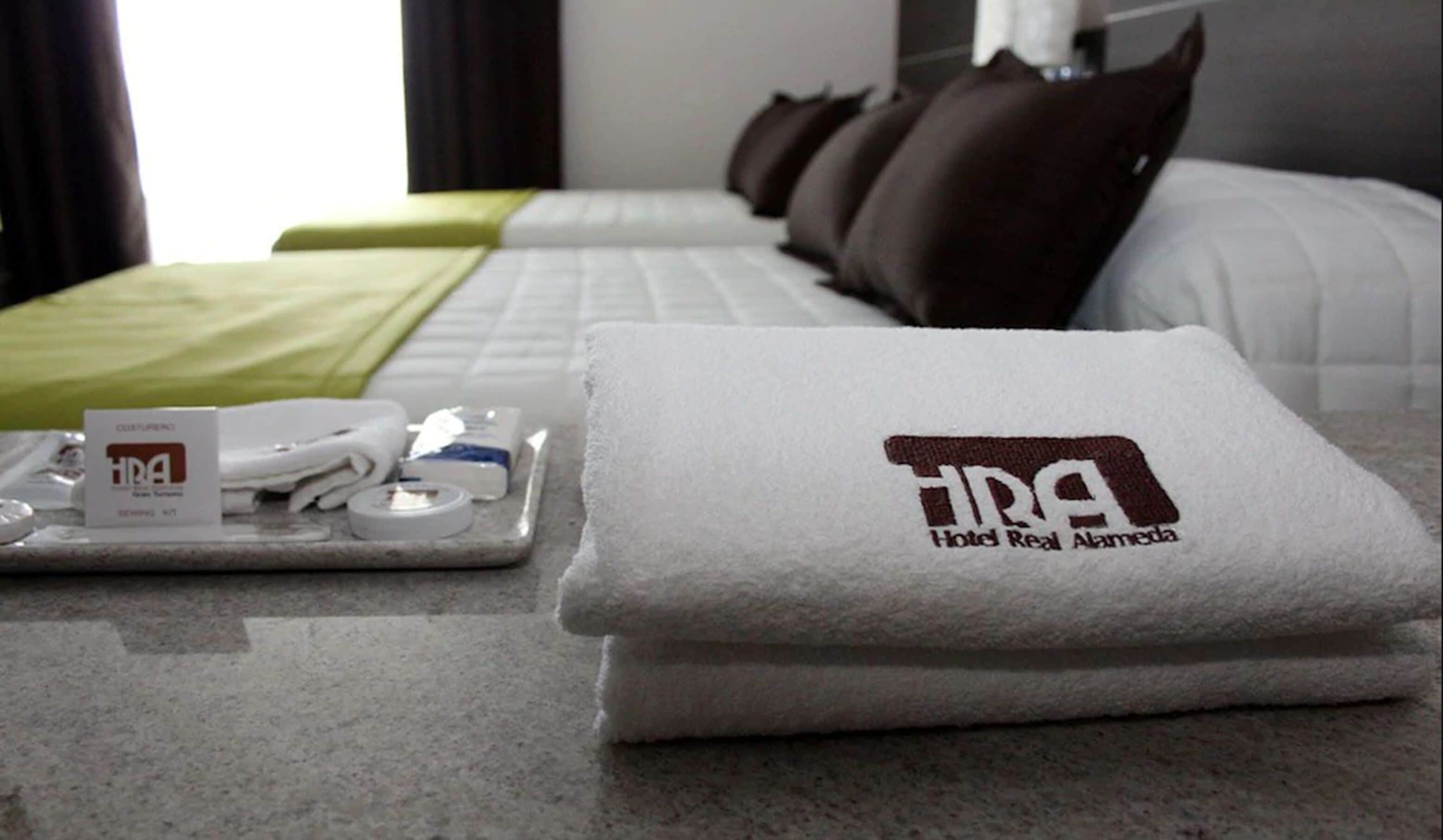 A neatly made bed with a folded towel and a tray of toiletries.