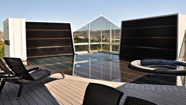 A rooftop terrace with a glass-enclosed infinity pool, a hot tub, and outdoor seating. - Hotel Real Alameda (Querétaro)