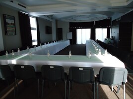 Un salón de conferencias con una larga mesa, sillas y botellas de agua.