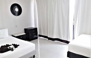 A bedroom with a bed, a bedside table, a black clock on the wall, and a curtain. - La Playa Condo (Playa del Carmen)