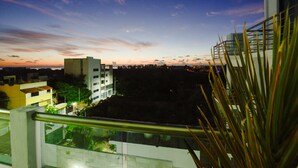 A balcony with a view of a cityscape at dusk, including buildings and a clear sky. - La Playa Condo (Playa del Carmen)