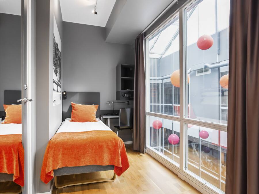 Habitación de hotel moderna con dos camas, ventanas amplias y vistas al exterior.