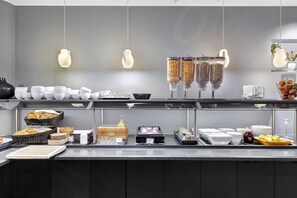 Montaje de bufé con diversos alimentos y recipientes, incluyendo tazones, cestas y dispensadores de condimentos.
