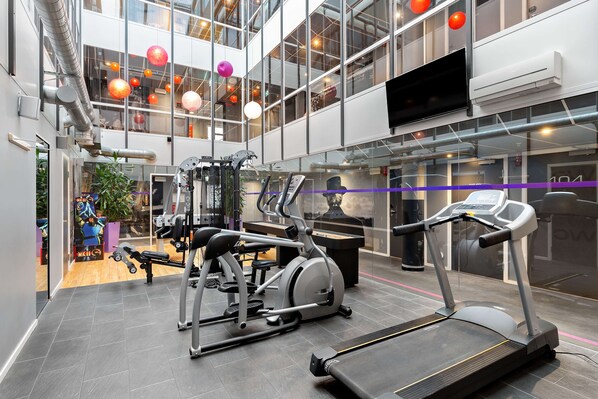 A modern gym with treadmills, elliptical machines, and weightlifting equipment.