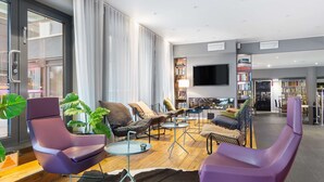 Un soggiorno moderno con poltrone viola, una televisione a schermo piatto e una libreria.
