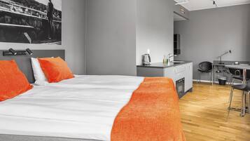 Une chambre d’hôtel moderne équipée d’un grand lit, d’un bureau et d’une kitchenette.